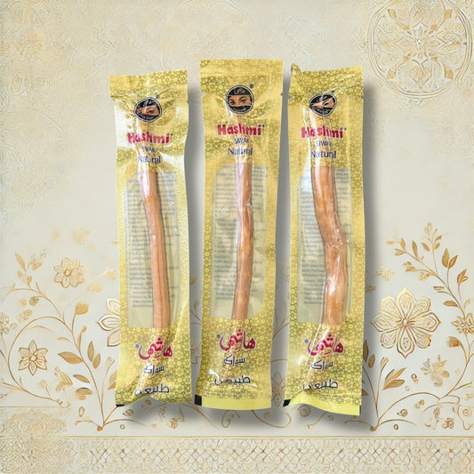 Drei Hashmi Siwak Stöcke nebeneinander, verpackt in gelber Folie mit arabischer Aufschrift auf traditionellem Hintergrund