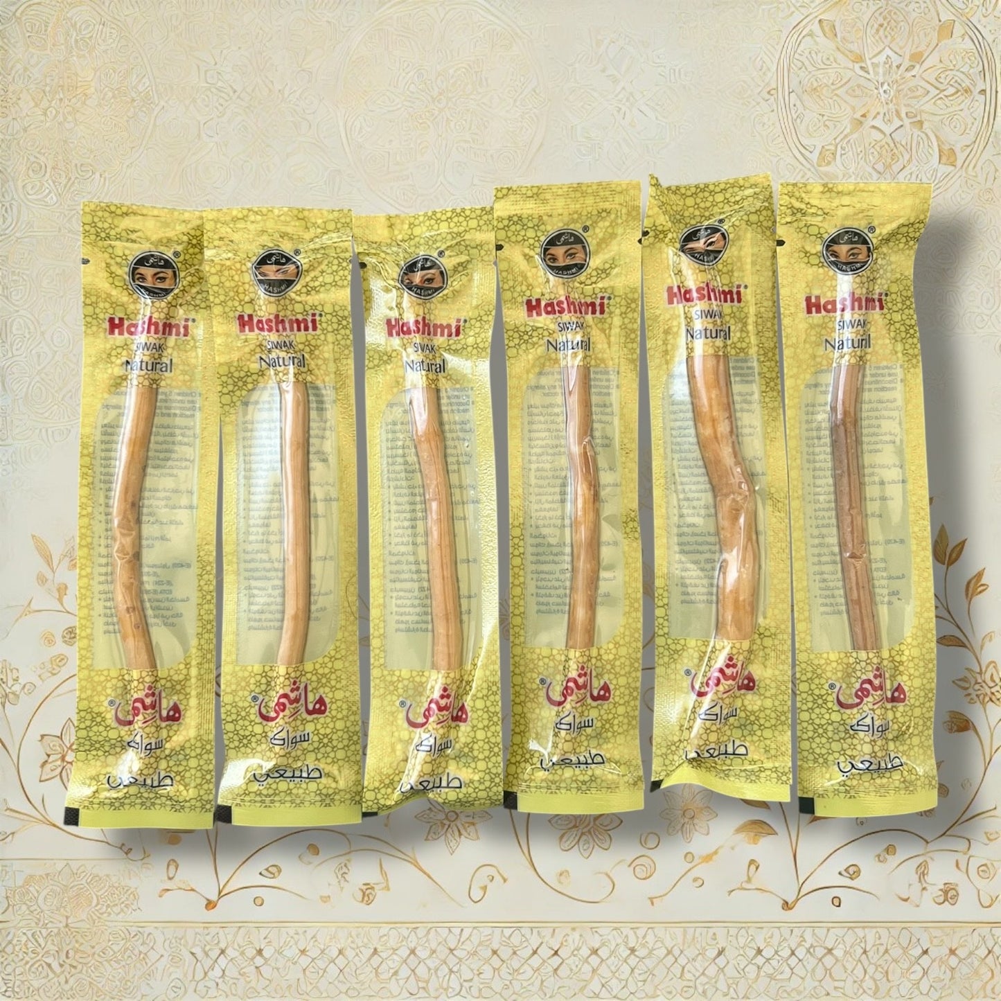 Sechs natürliche Hashmi Siwak Stöcke in hygienischer Einzelverpackung, nebeneinander auf dekorativem Hintergrund angeordnet

